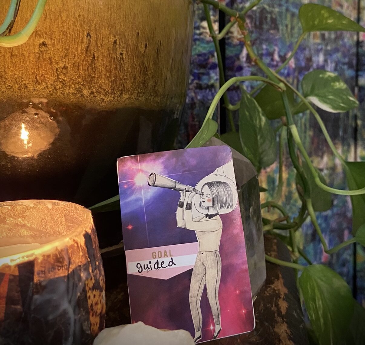 candle and plant surrounds an artist trading card with collage of girl with monocular looking for fulfillment