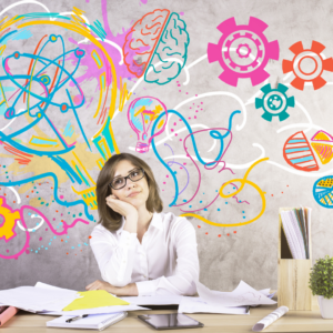 woman at a messy desk with drawings floating over her head. Art is as way to organize your thoughts and non-verbal expression. art therapy for work