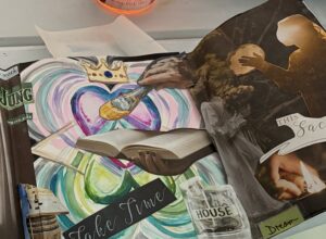 Close-up of a vision board collage with the words ‘take time,’ a watercolor heart with a crown, and a hand holding a paintbrush — symbolizing reflection, intention setting, and creative renewal.